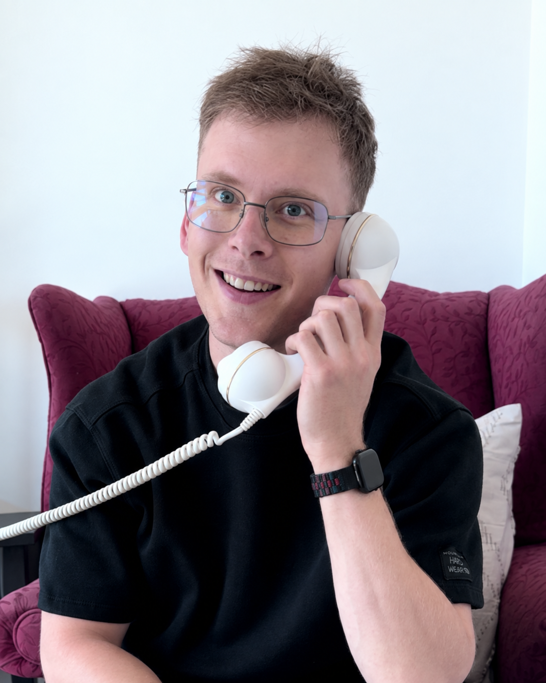 Olivier smiling while holding a white telephone receiver
